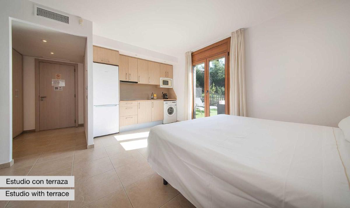 Un dormitorio con una cama blanca y una cocina. en Sono & SPA - Adults Only, en La Garriga