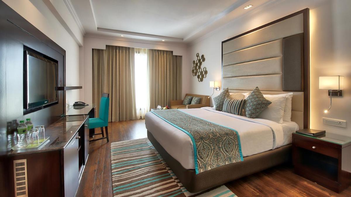 a hotel room with a large bed and a television at Radisson Jaipur City Center in Jaipur