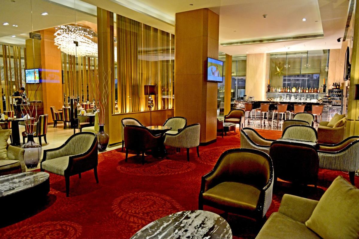 a hotel lobby with a bar and tables and chairs at Radisson Blu Jaipur in Jaipur