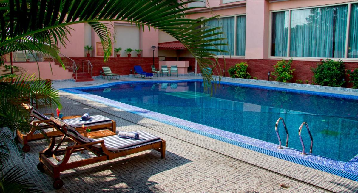 a swimming pool with a table and chairs next to a building at The Piccadily in Lucknow