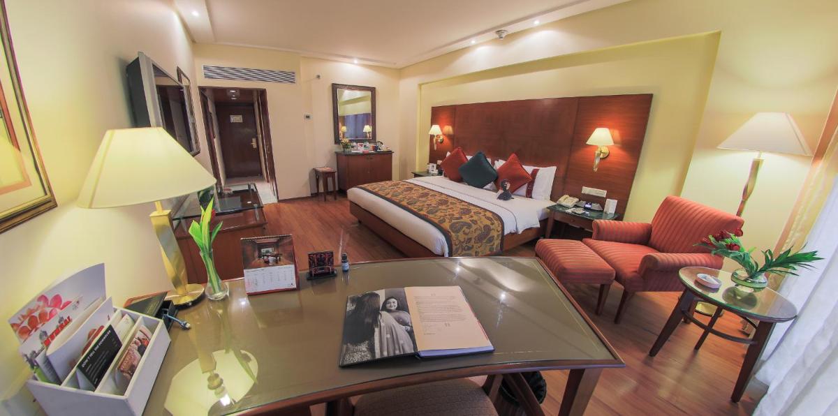 a hotel room with a bed and a desk at The Lalit Mumbai in Mumbai