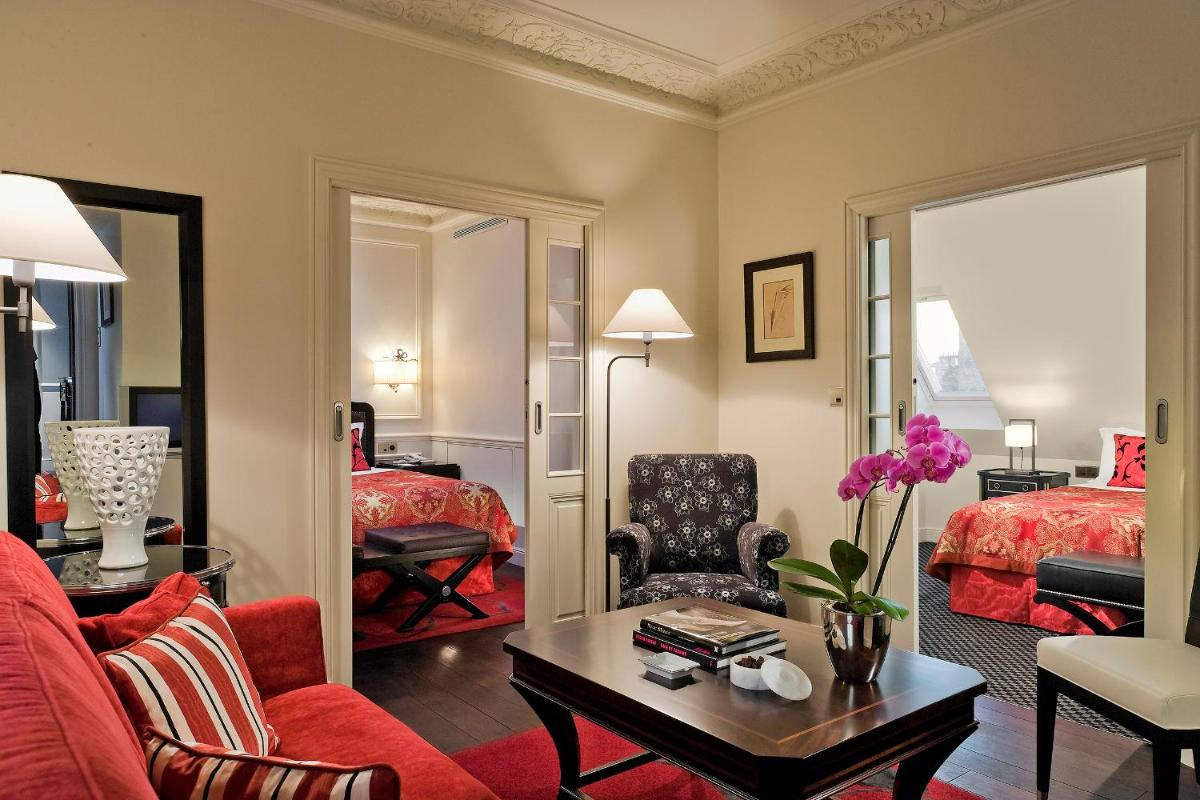 un salon avec un canapé rouge et une chambre dans l'établissement Hôtel Keppler, à Paris
