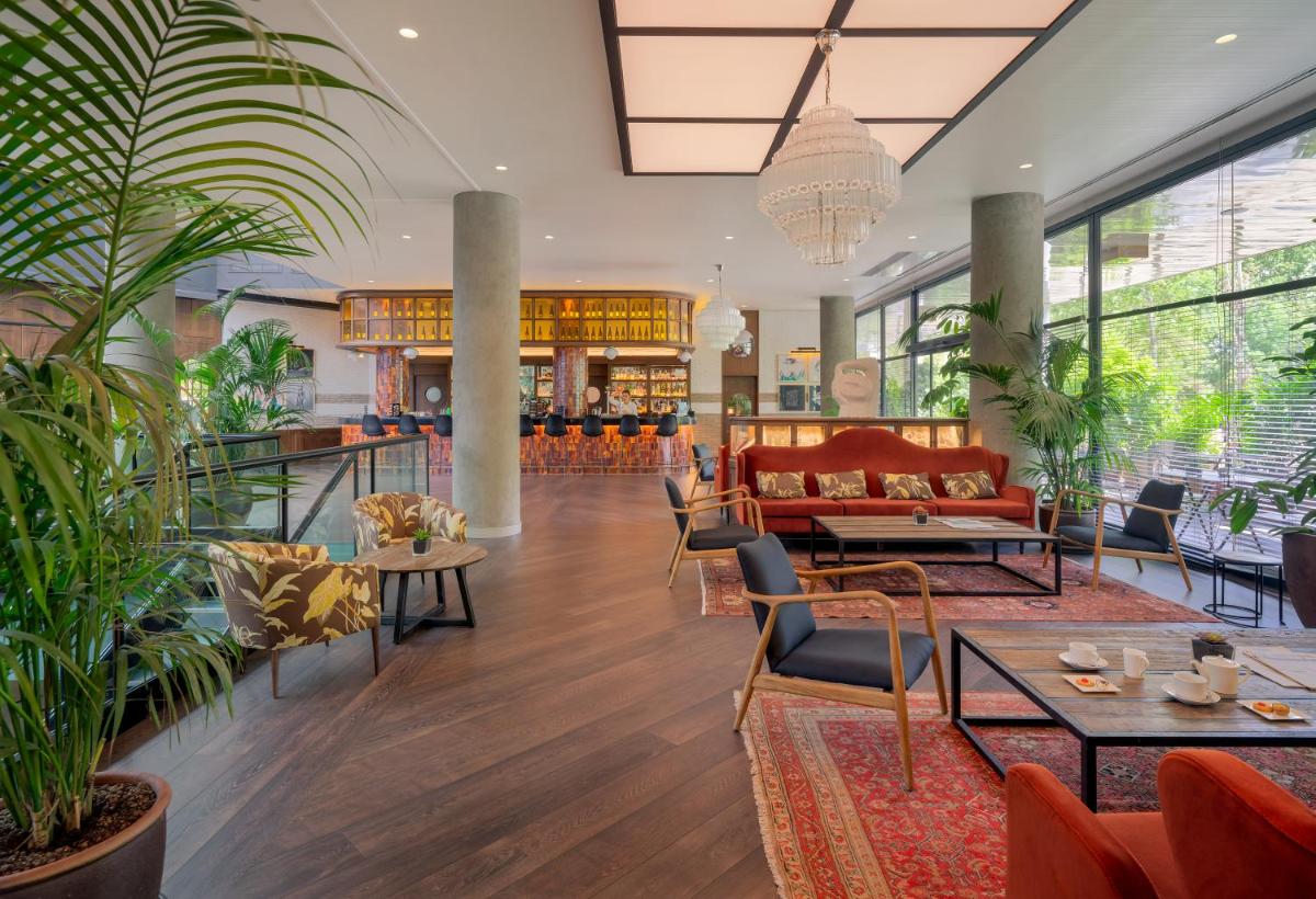 un vestíbulo con muebles y plantas en un edificio en H10 Marina Barcelona, en Barcelona