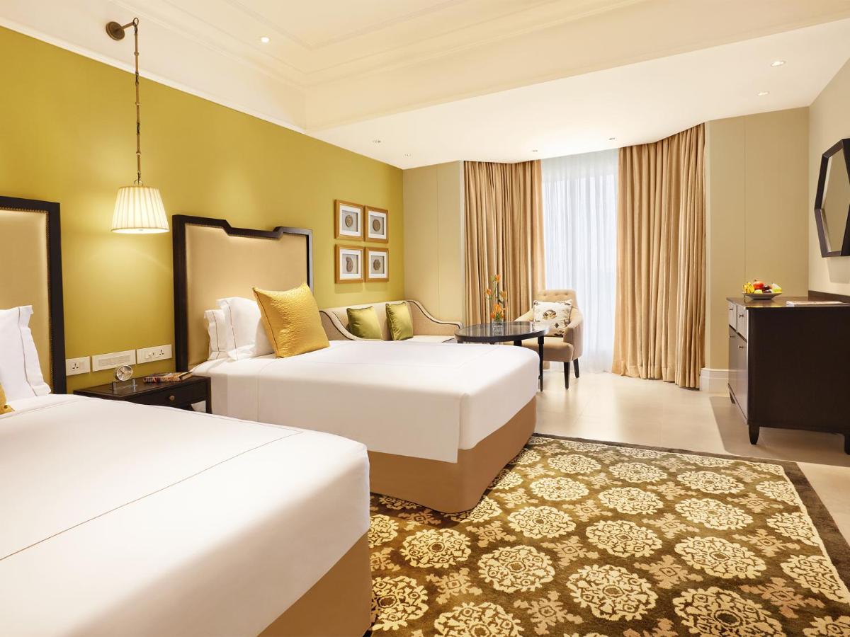 a hotel room with two beds and a desk at Taj Connemara, Chennai in Chennai