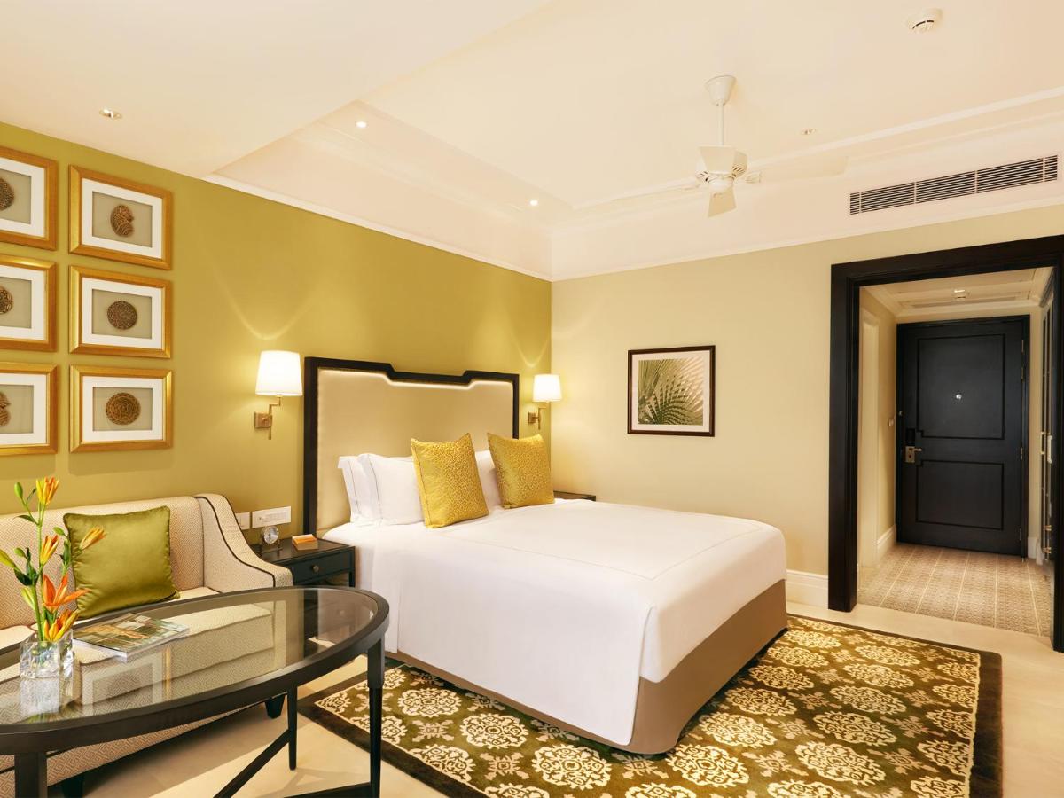 a bedroom with a bed and a glass table at Taj Connemara, Chennai in Chennai