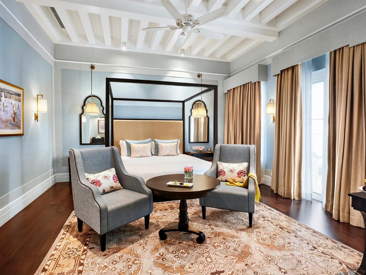 a bedroom with a bed and two chairs and a table at Taj Connemara, Chennai in Chennai
