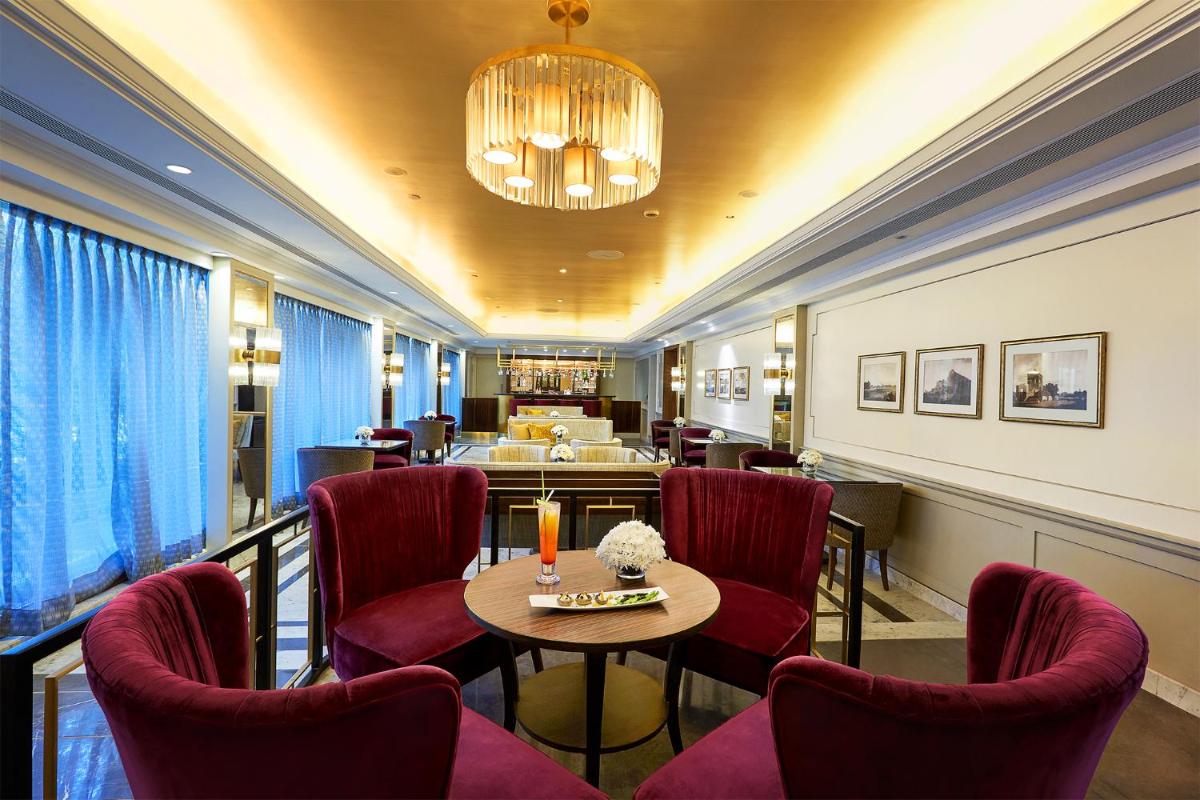 a room with chairs and a table and a chandelier at Taj Connemara, Chennai in Chennai