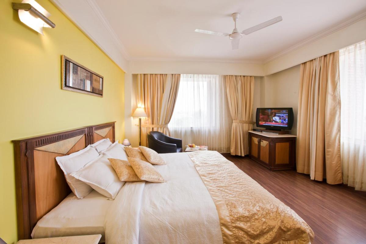 a hotel room with a bed and a television at The Piccadily in Lucknow