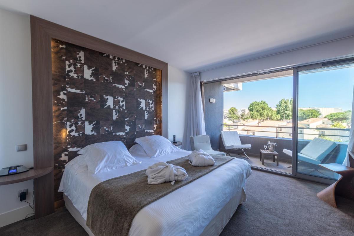une chambre avec un grand lit et une grande fenêtre dans l'établissement Oz'Inn Hôtel & Spa, au Cap d'Agde