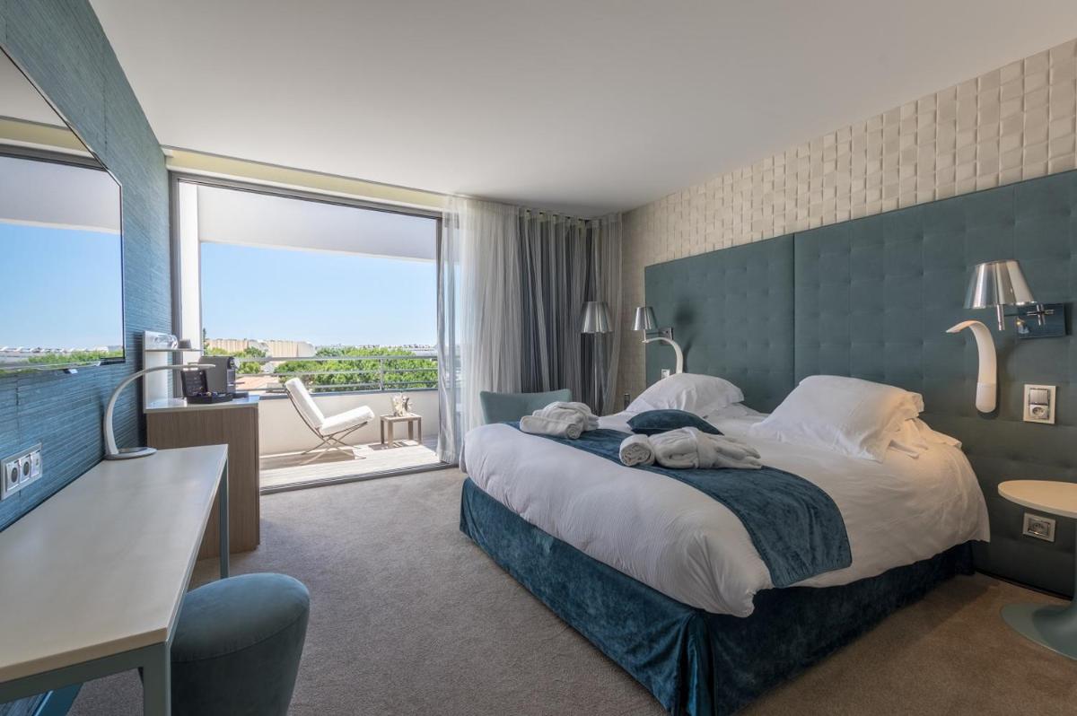 une chambre d'hôtel avec un lit et une grande fenêtre dans l'établissement Oz'Inn Hôtel & Spa, au Cap d'Agde