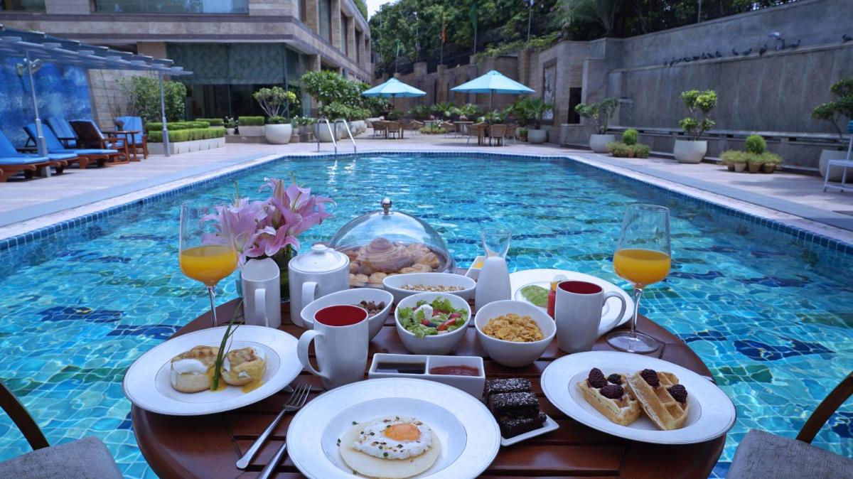 a table with food and drinks next to a swimming pool at Jaypee Siddharth in New Delhi a table with food and drinks next to a swimming pool at Jaypee Siddharth in New Delhi