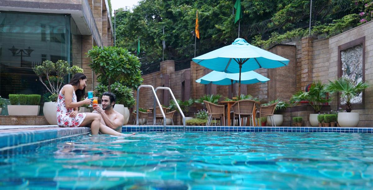 a man and a woman sitting next to a swimming pool at Jaypee Siddharth in New Delhi a man and a woman sitting next to a swimming pool at Jaypee Siddharth in New Delhi