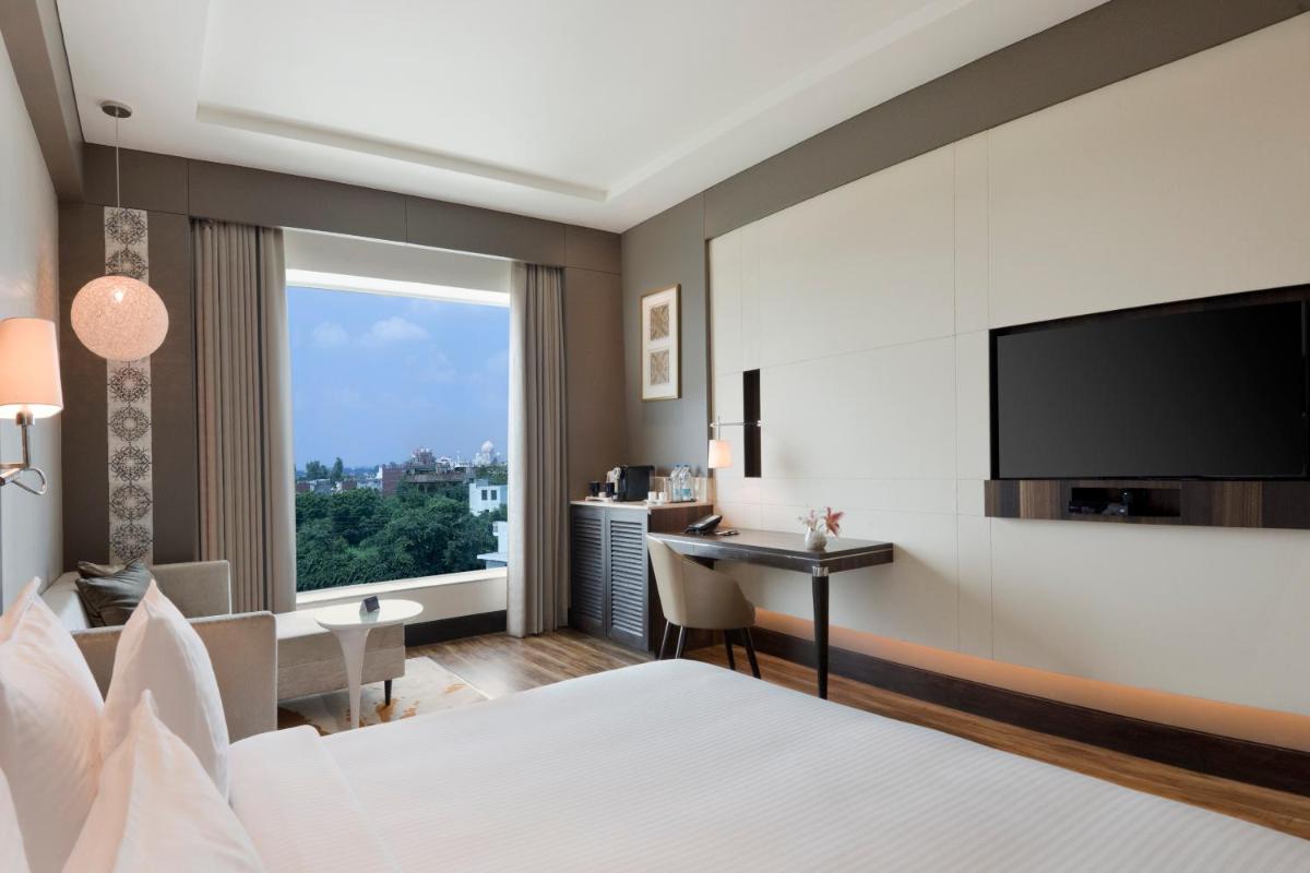 a hotel room with a bed and a desk and a television at Taj Agra in Agra