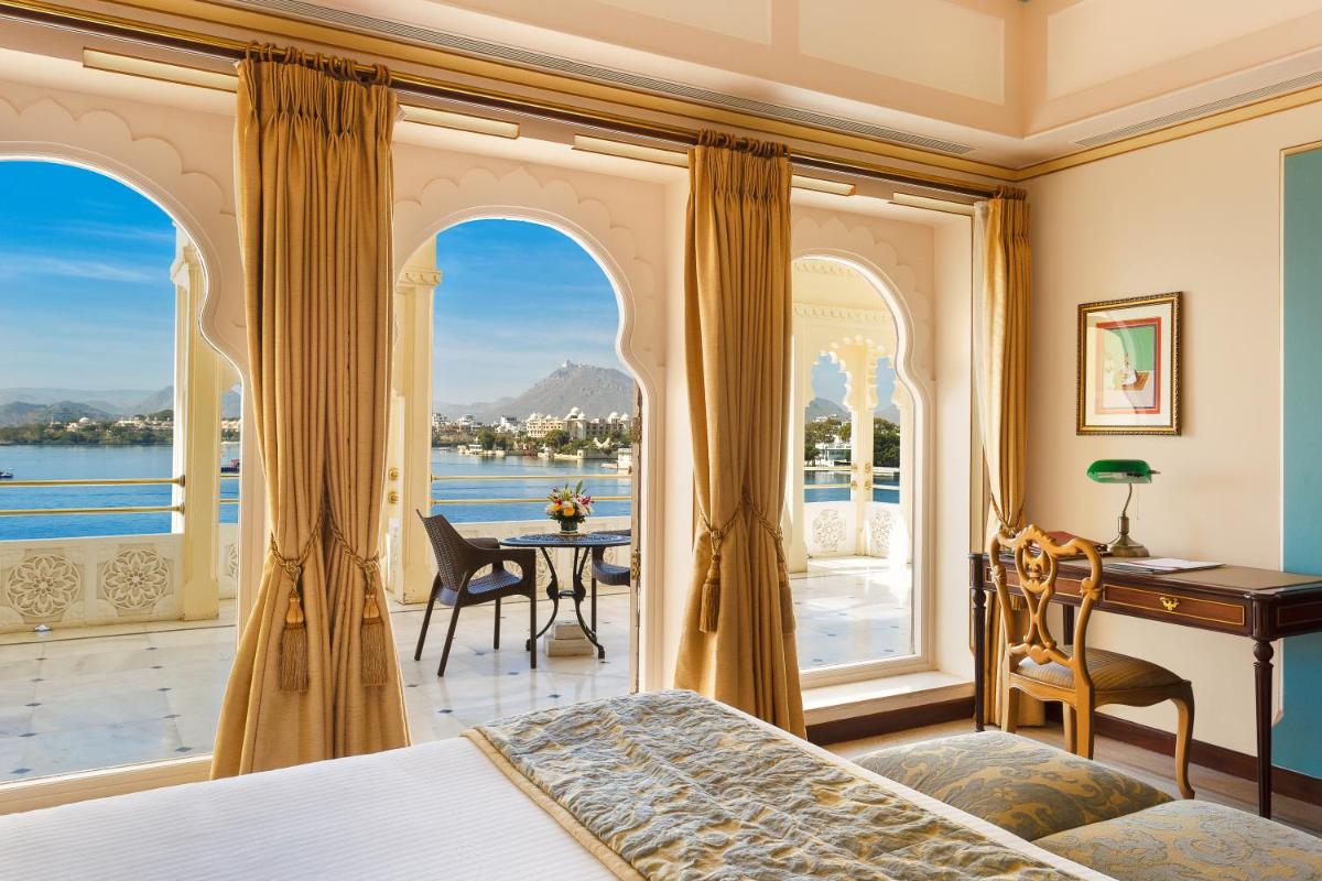 a bedroom with a bed and a desk and a balcony at Taj Fateh Prakash Palace Udaipur in Udaipur
