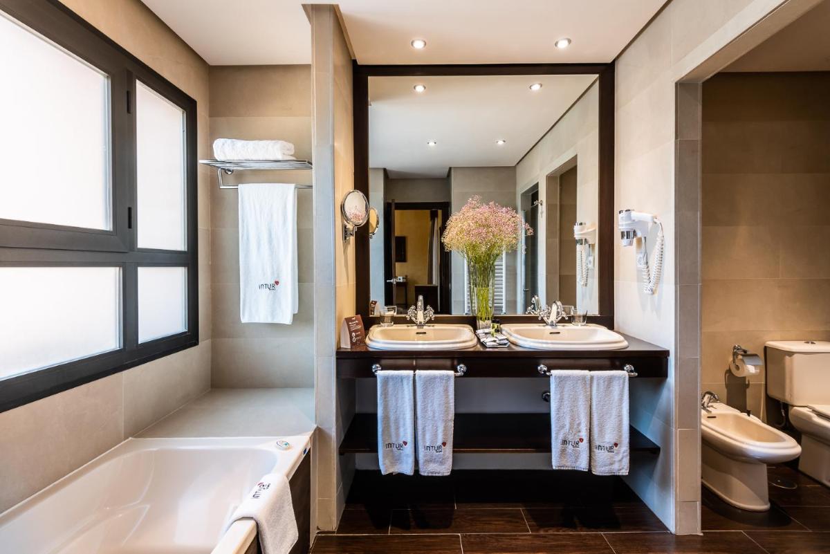 Un baño con dos lavabos, una bañera y un espejo. en Intelier Airén, en Alcázar de San Juan