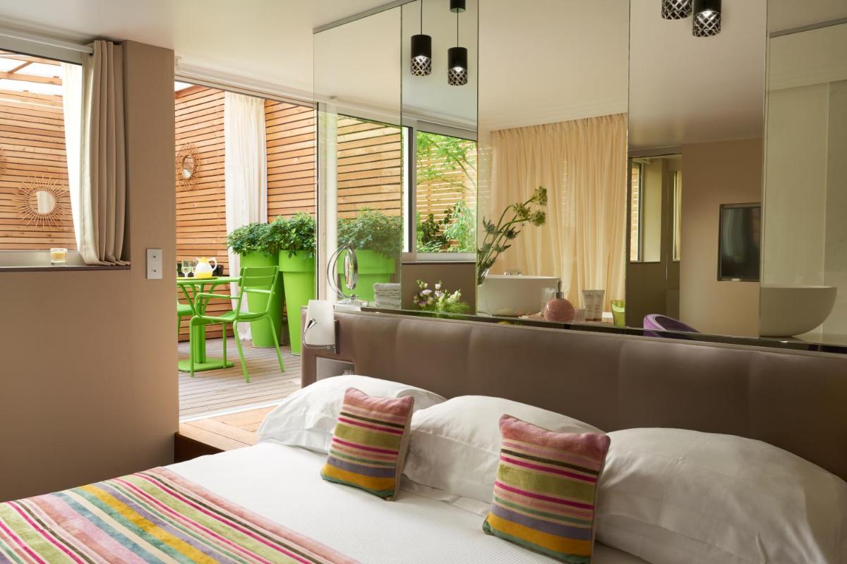 une chambre avec un lit et un grand miroir dans l'établissement Le Mathurin Hotel & Spa, à Paris