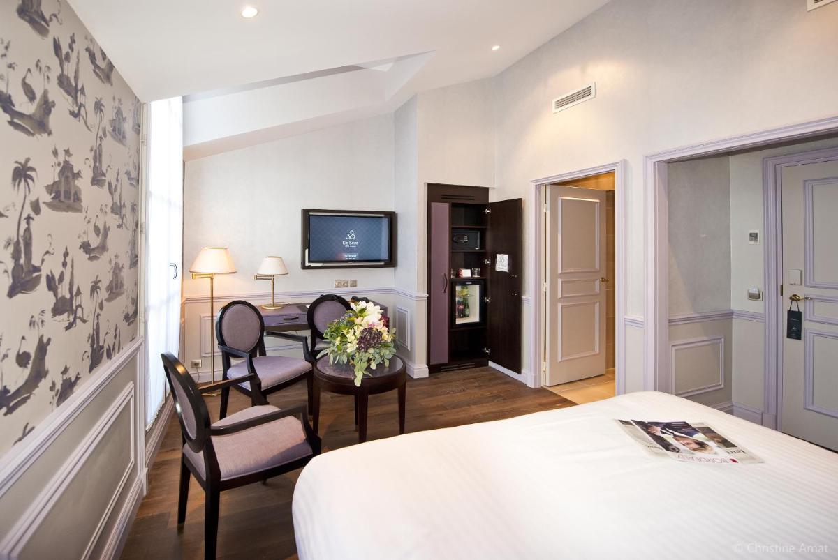 une chambre d'hôtel avec un lit, une table et des chaises dans l'établissement Hôtel de Sèze & Spa Bordeaux Centre, à Bordeaux