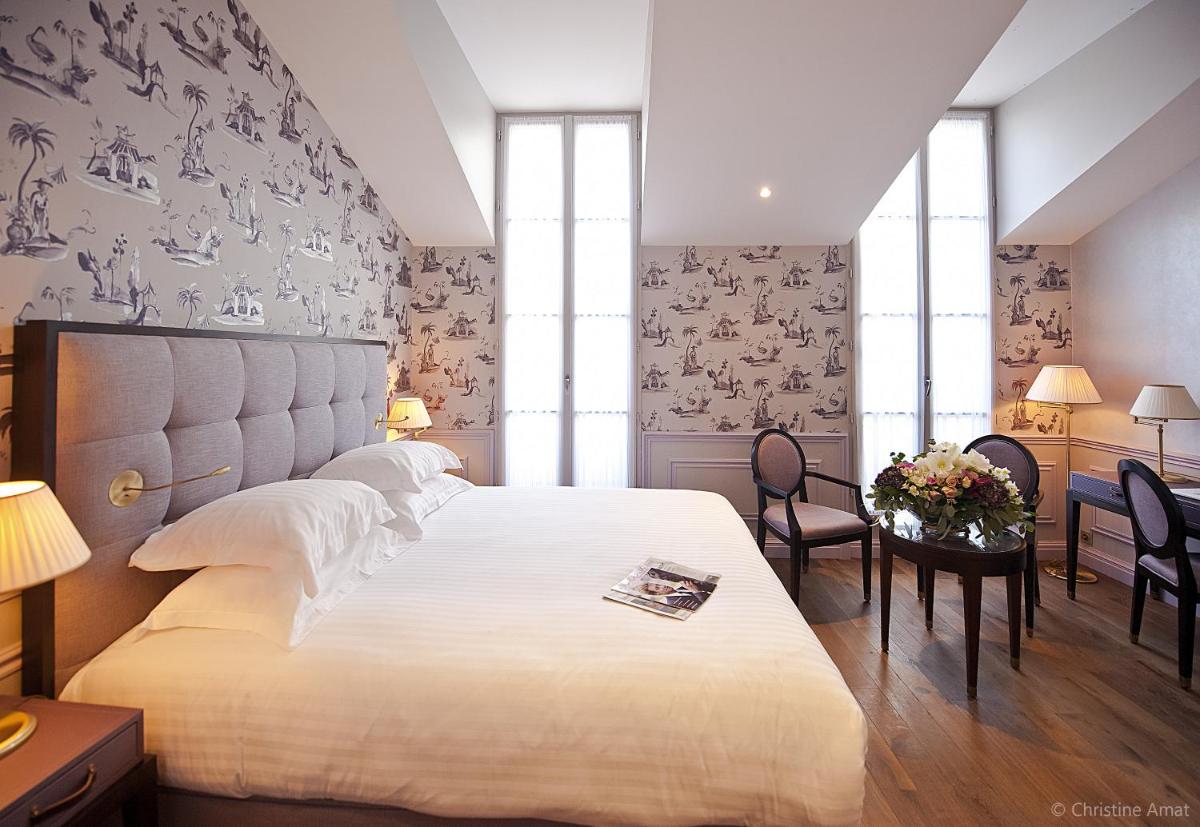une chambre avec un grand lit et une table et des chaises dans l'établissement Hôtel de Sèze & Spa Bordeaux Centre, à Bordeaux 99 autres photos