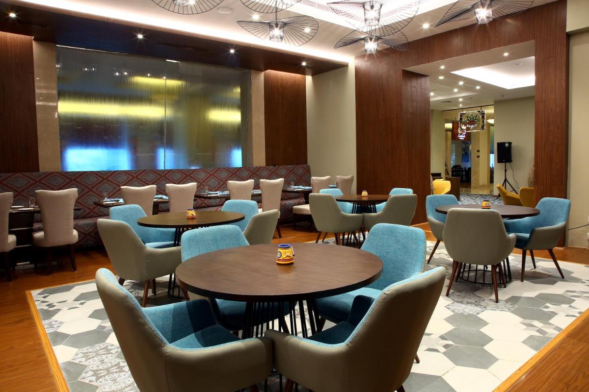 a restaurant with tables and chairs in a lobby at Radisson Hyderabad Hitec City in Hyderabad