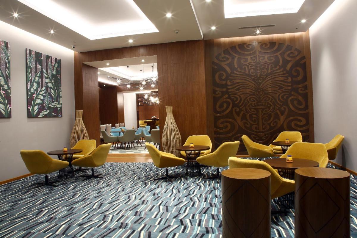 a waiting room with yellow chairs and tables at Radisson Hyderabad Hitec City in Hyderabad