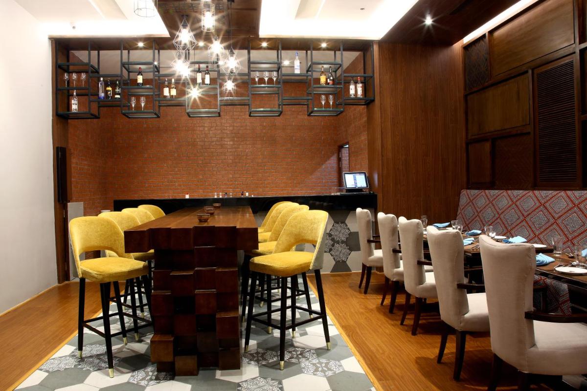 a dining room with a long table and yellow chairs at Radisson Hyderabad Hitec City in Hyderabad