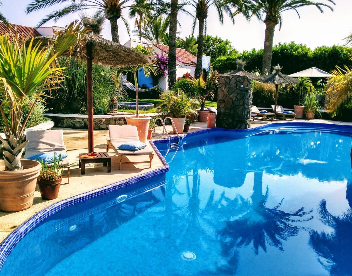 Una gran piscina azul con sillas y palmeras. en Birdcage Gay Men Resort and Lifestyle Hotel, en Playa del Inglés