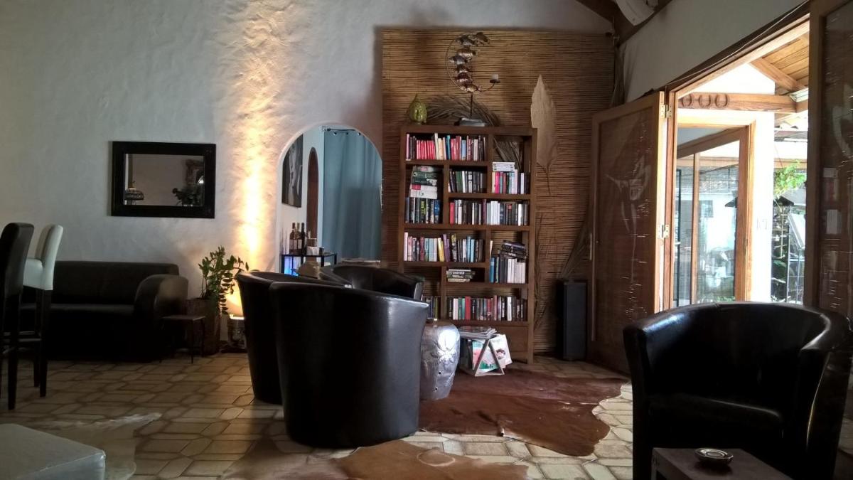una habitación con sillas y una estantería con libros en Birdcage Gay Men Resort and Lifestyle Hotel, en Playa del Inglés
