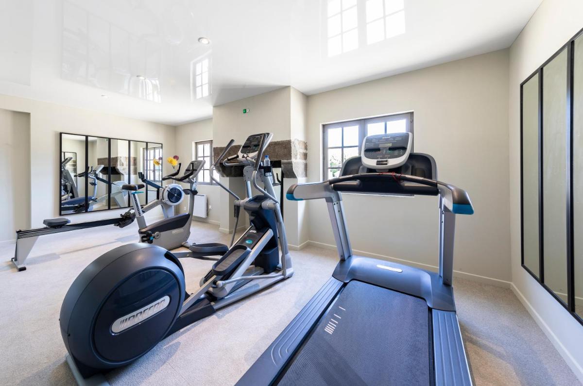 une salle de sport avec des tapis de course et des vélos elliptiques dans l'établissement Hotel de L'Abbaye Le Tronchet - Handwritten Collection, au Tronchet