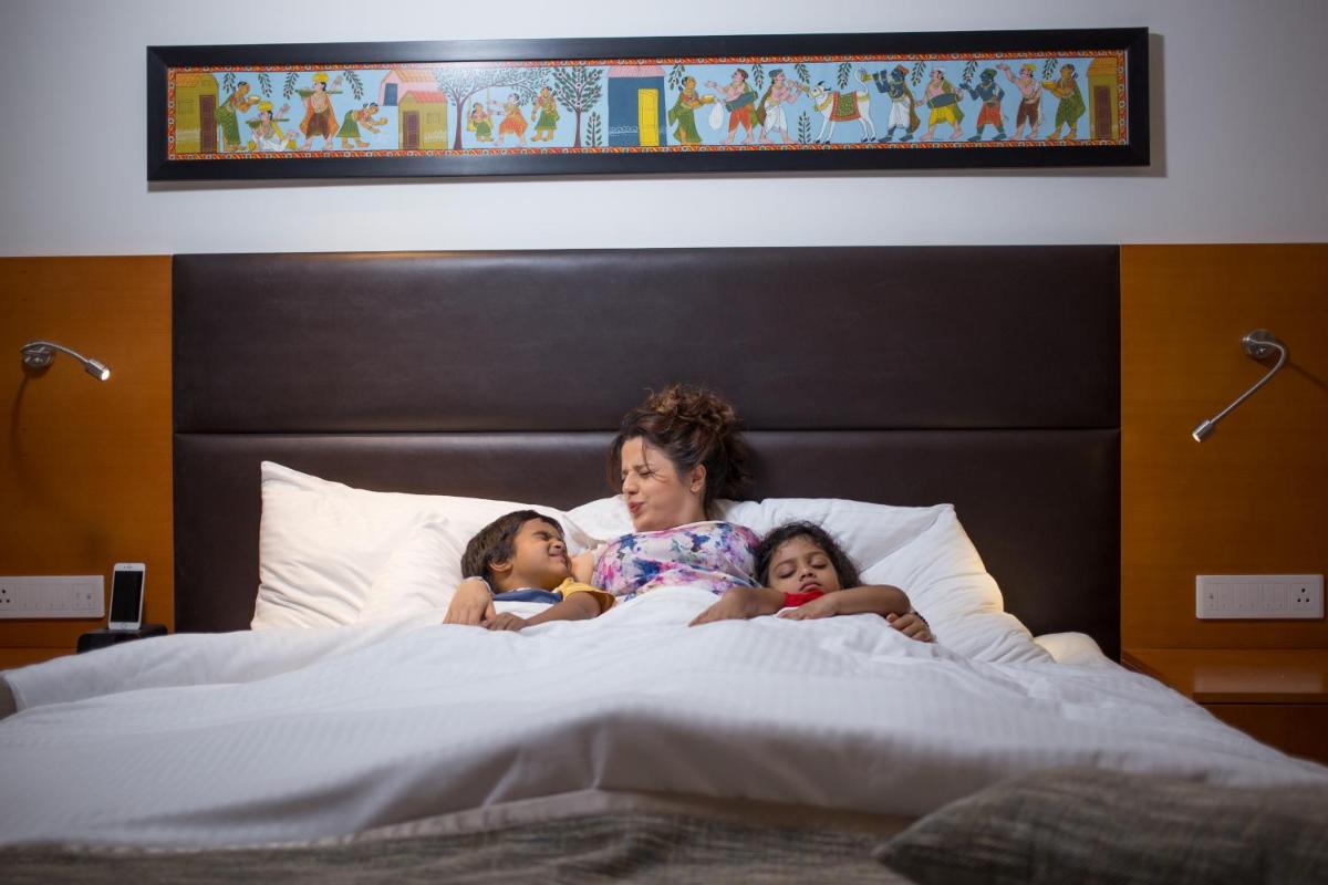 a woman and two children laying in a bed at Mercure Hyderabad KCP Banjara Hills, An Accor Hotel in Hyderabad