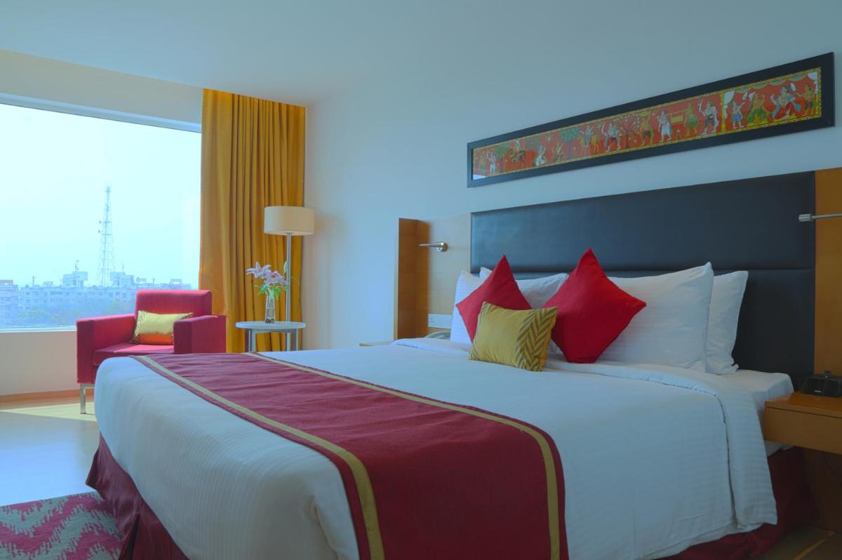 a hotel room with a large bed with red pillows at Mercure Hyderabad KCP Banjara Hills, An Accor Hotel in Hyderabad