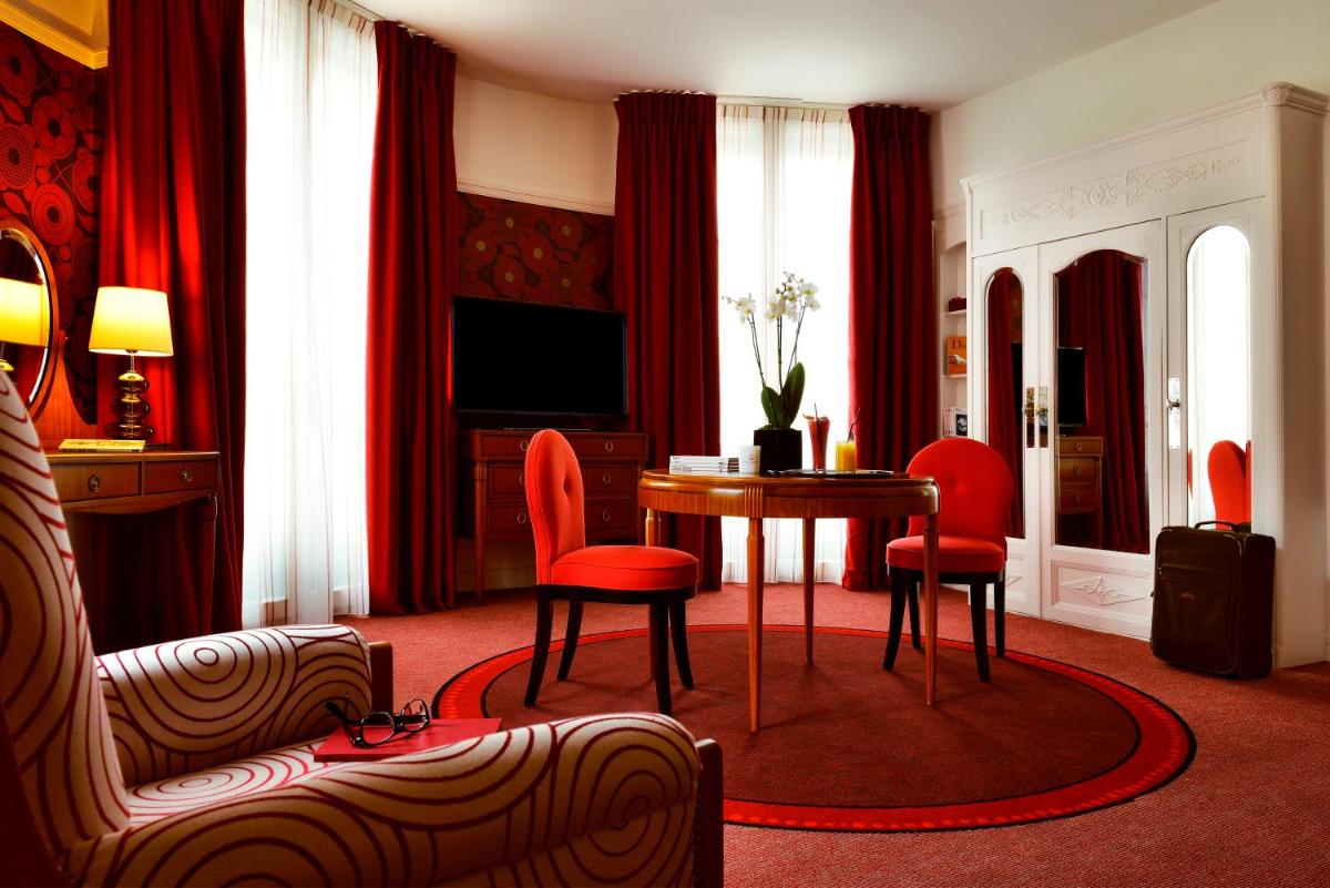 un salon avec une table et des chaises rouges dans l'établissement Carlton Hotel Lyon - MGallery Collection, à Lyon