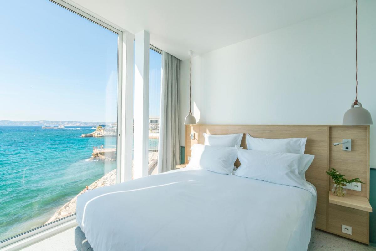 une chambre avec un grand lit avec vue sur l'océan dans l'établissement Les Bords De Mer, à Marseille