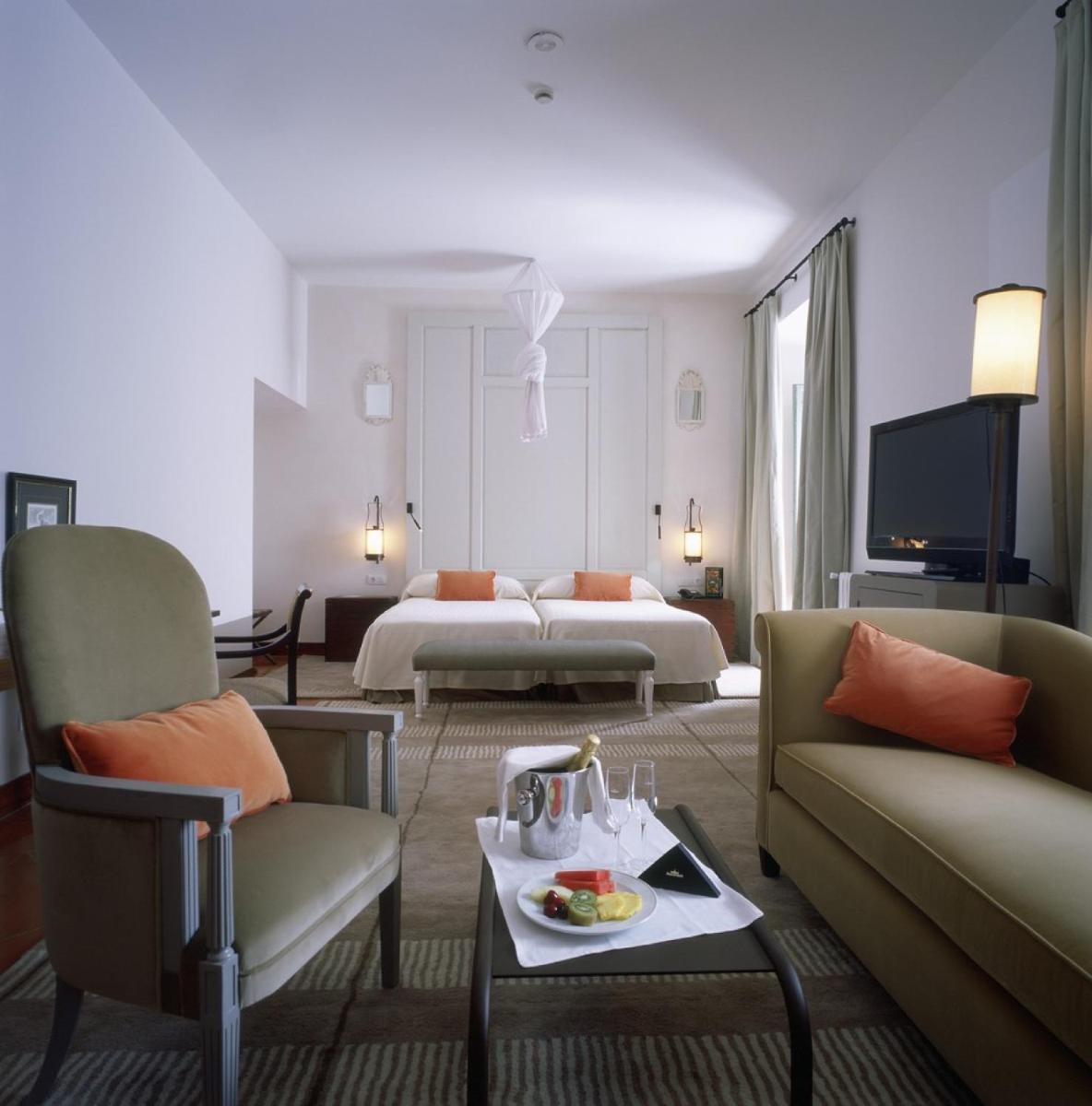 Una habitación de hotel con dos camas y una sala de estar. en Parador de La Granja, en La Granja de San Ildefonso