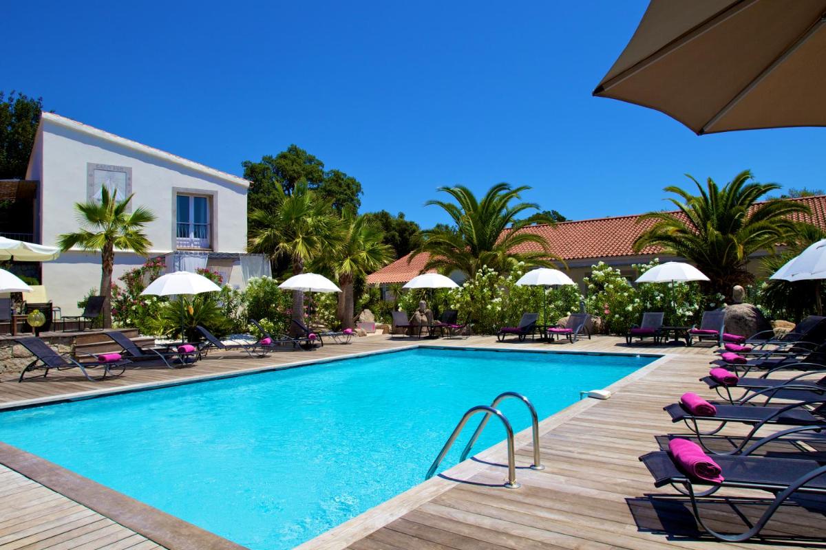 une piscine avec chaises longues et parasols à côté d'un complexe hôtelier dans l'établissement Golfe Hôtel & Spa Porto-Vecchio, à Porto-Vecchio