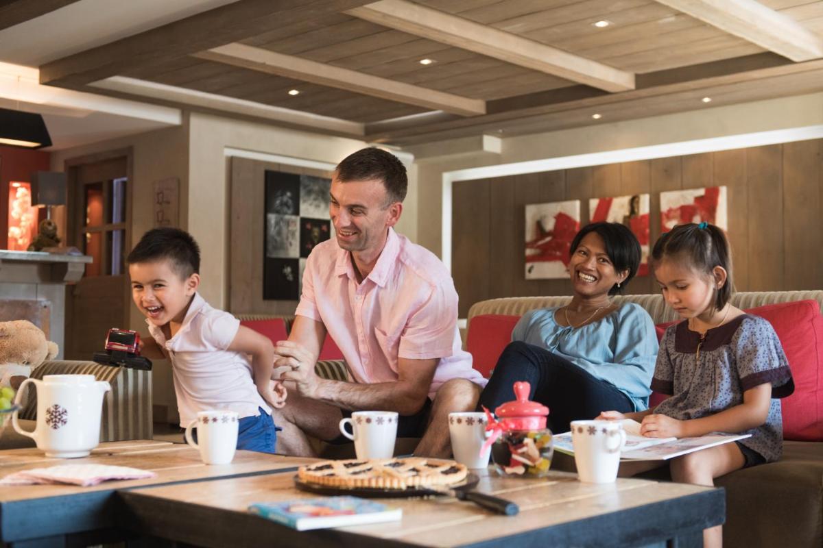 Un homme et une famille assis autour d'une table dans l'établissement CGH Résidence Boutique Le Chalet des Dolines, à Montgenèvre
