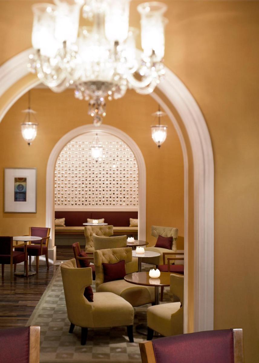 a restaurant with a chandelier and tables and chairs at Jai Mahal Palace in Jaipur