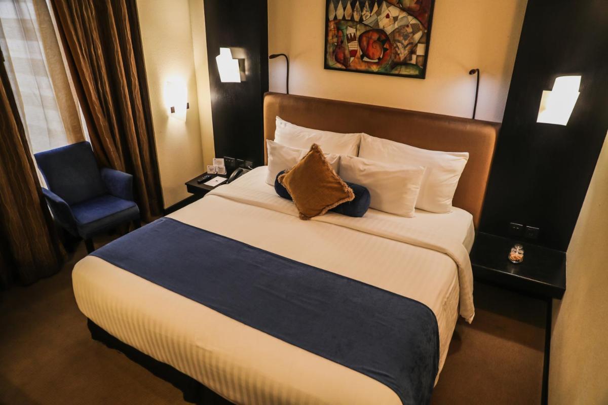 a hotel room with a bed and a chair at Sterlings Mac Hotel in Bengaluru