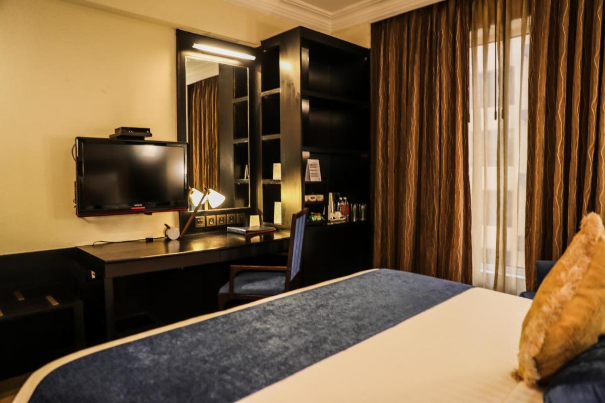 a hotel room with a bed and a desk and a television at Sterlings Mac Hotel in Bengaluru