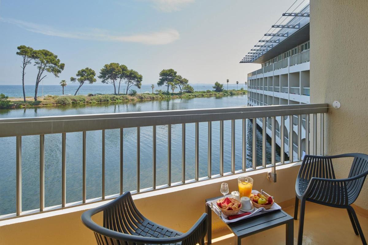 - un balcon avec deux chaises et une table avec de la nourriture et des boissons dans l'établissement Hotel Club Le Plein Sud Vacances Bleues, à Hyères