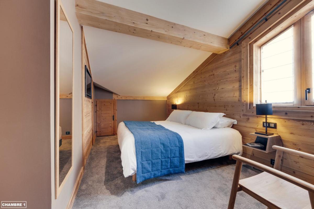 une chambre avec un lit dans une pièce aux murs en bois dans l'établissement Hôtel Avancher, à Val dʼIsère 111 autres photos