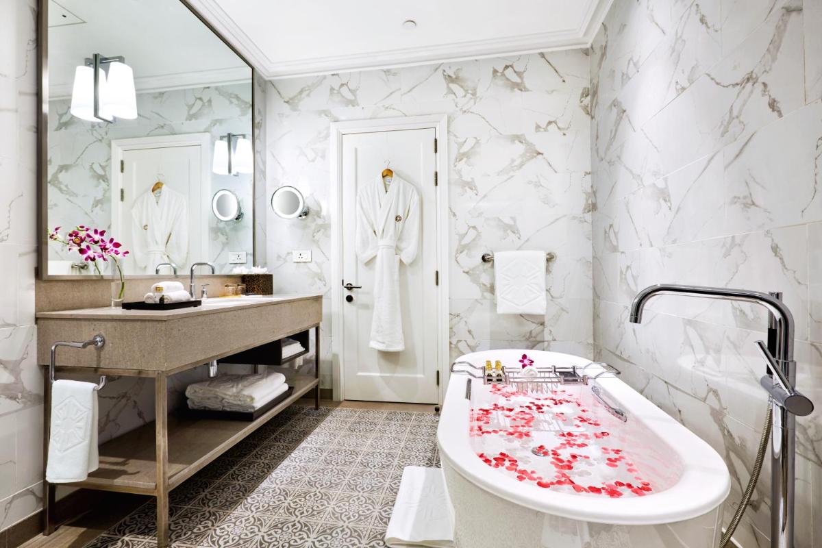 a bathroom with a tub and a sink and a mirror at Taj Connemara, Chennai in Chennai