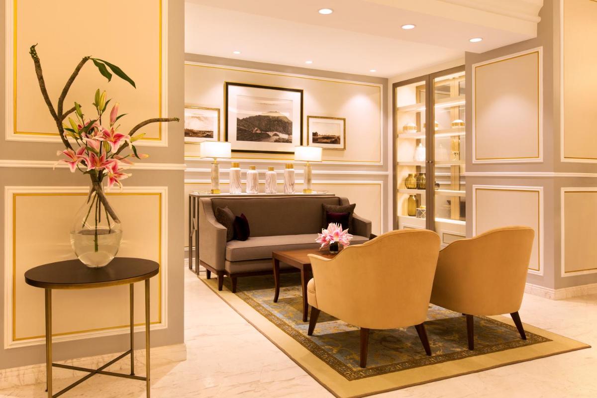 a living room with a couch and a table and chairs at Taj Connemara, Chennai in Chennai