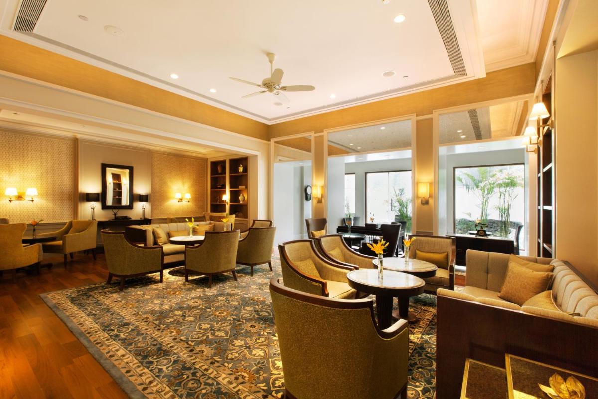 a hotel lobby with tables and chairs and a bar at Taj Connemara, Chennai in Chennai