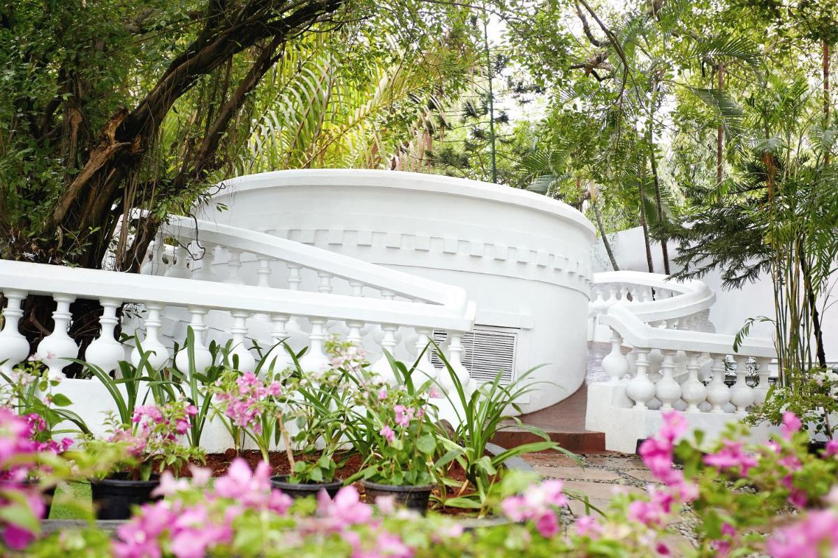 a white fence in a garden with flowers at Taj Connemara, Chennai in Chennai