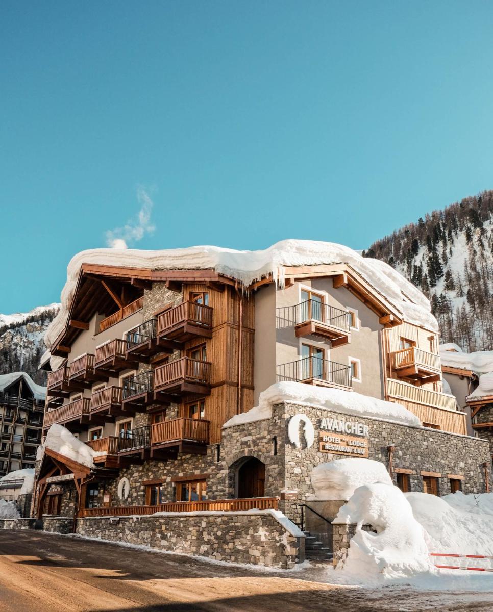 un grand bâtiment avec de la neige dessus dans l'établissement Hôtel Avancher, à Val dʼIsère