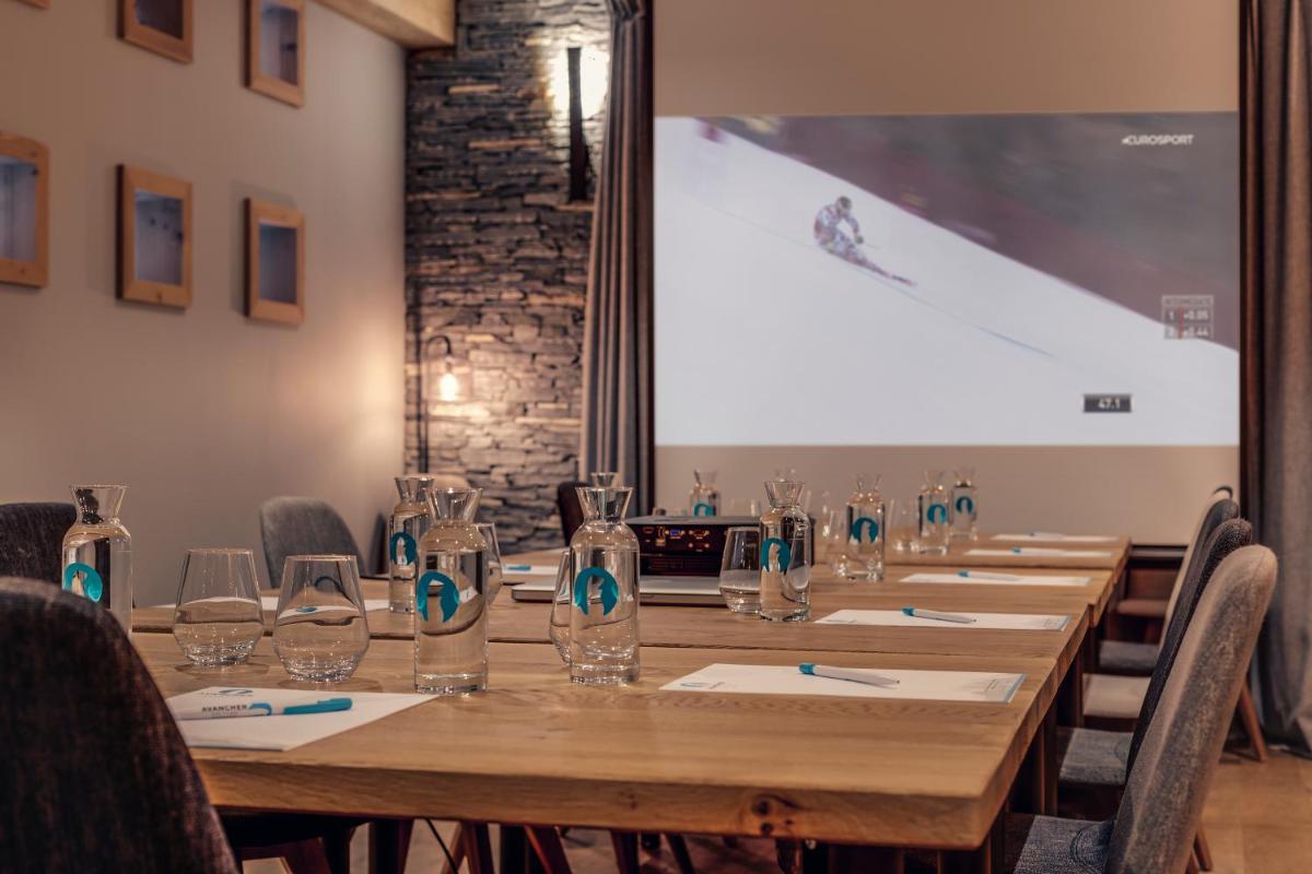 une longue table dans une pièce avec écran de projection dans l'établissement Hôtel Avancher, à Val dʼIsère