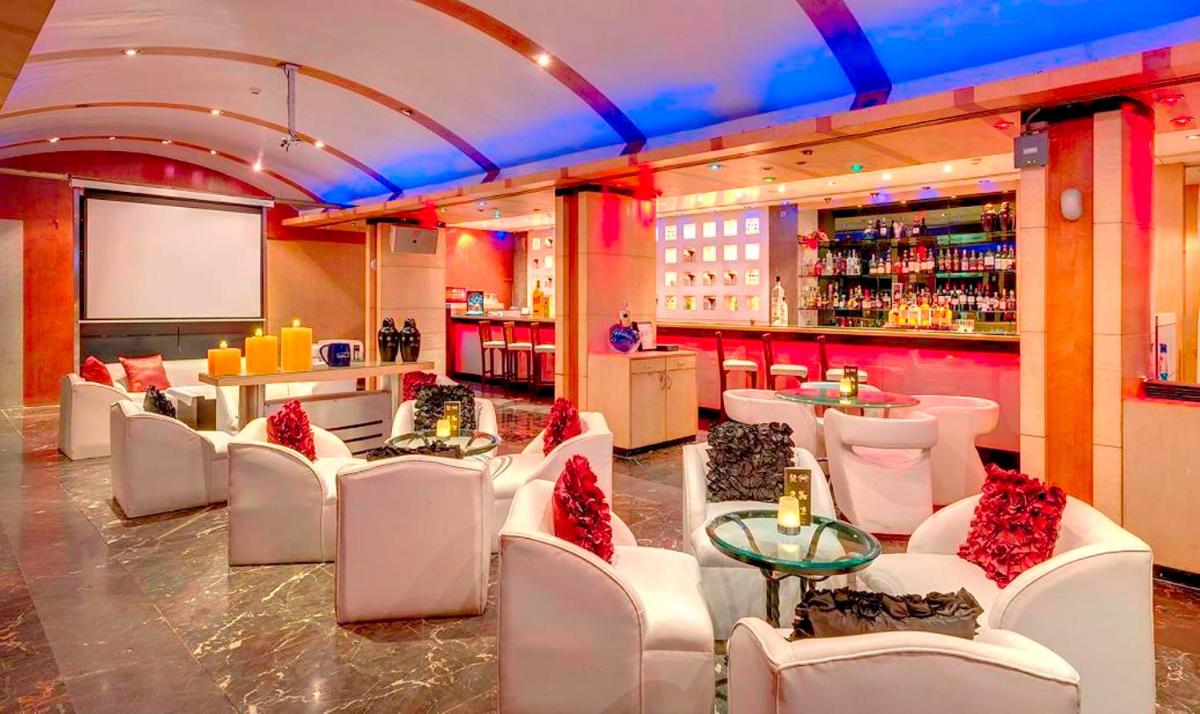 a restaurant with white chairs and a bar at Hotel Hindusthan International, Kolkata in Kolkata