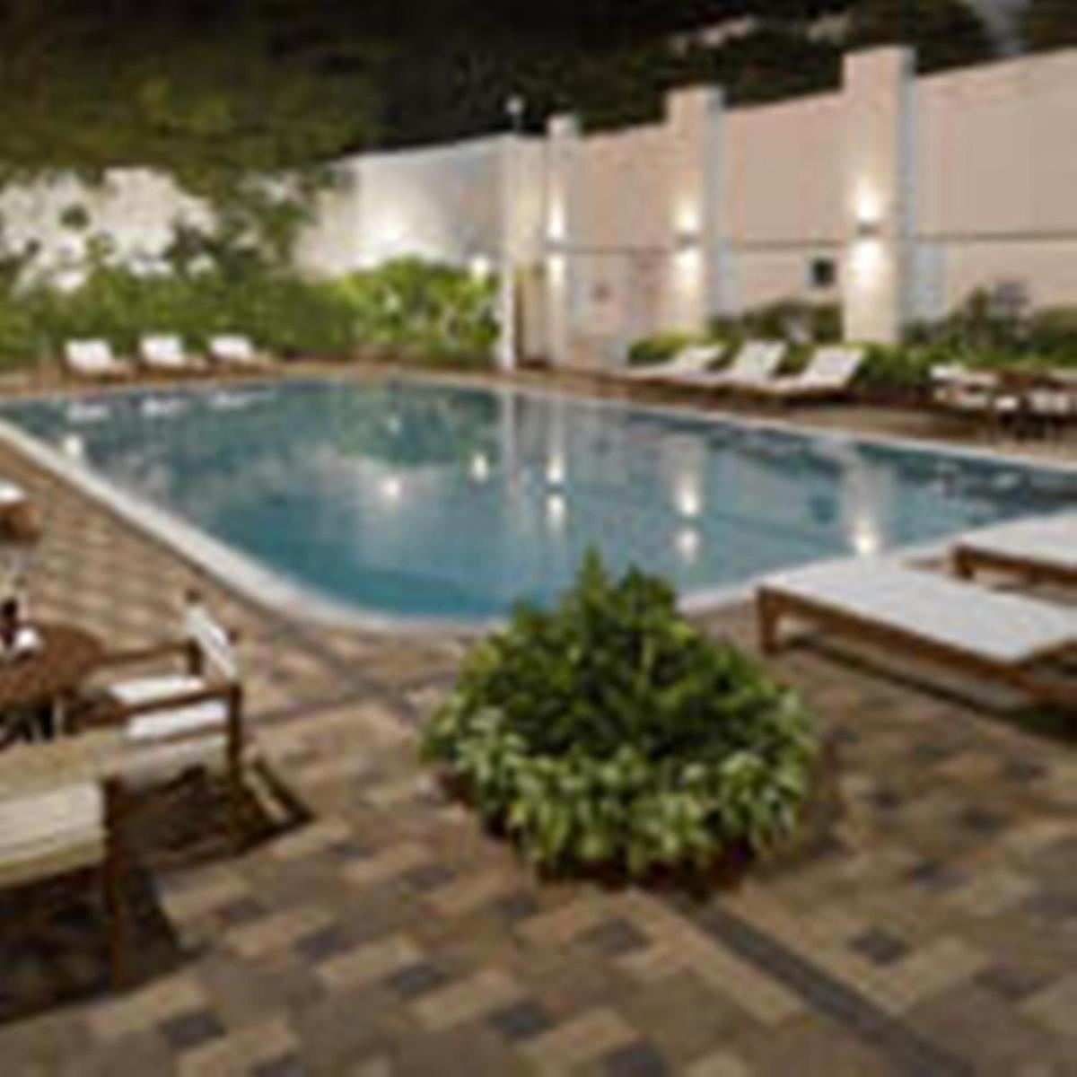 a large swimming pool with chairs at Hotel Hindusthan International, Kolkata in Kolkata
