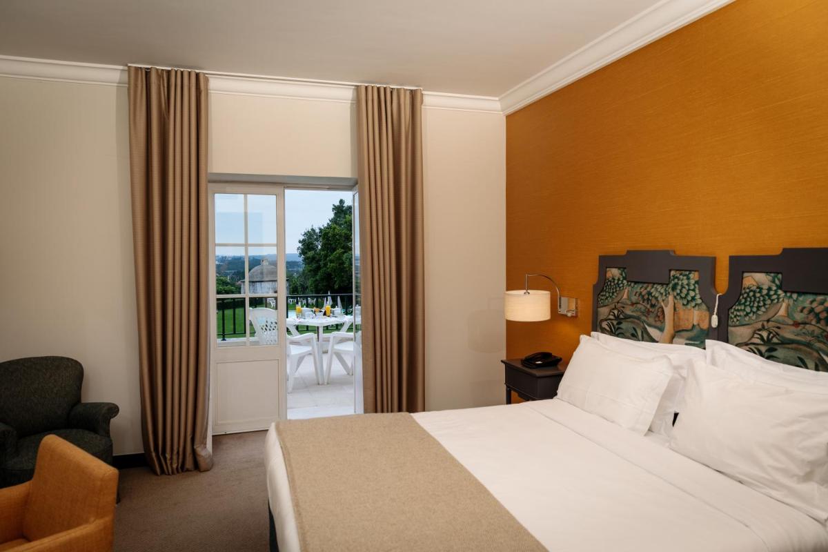 um quarto de hotel com uma cama e uma varanda em Conimbriga Hotel do Paço em Condeixa a Nova
