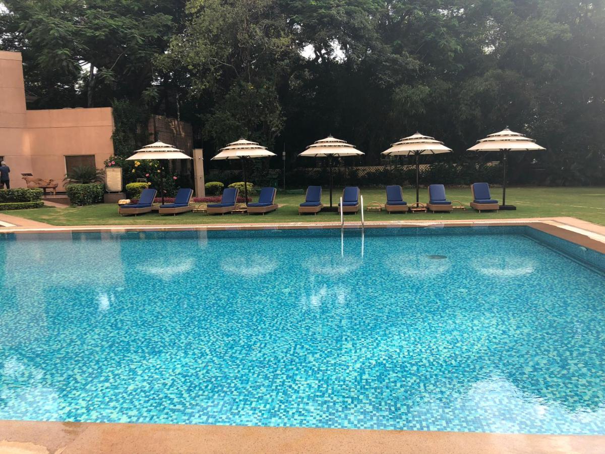 a swimming pool with chairs and umbrellas at The Lalit Ashok in Bengaluru a swimming pool with chairs and umbrellas at The Lalit Ashok in Bengaluru